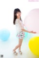 A young woman standing in front of a bunch of balloons.